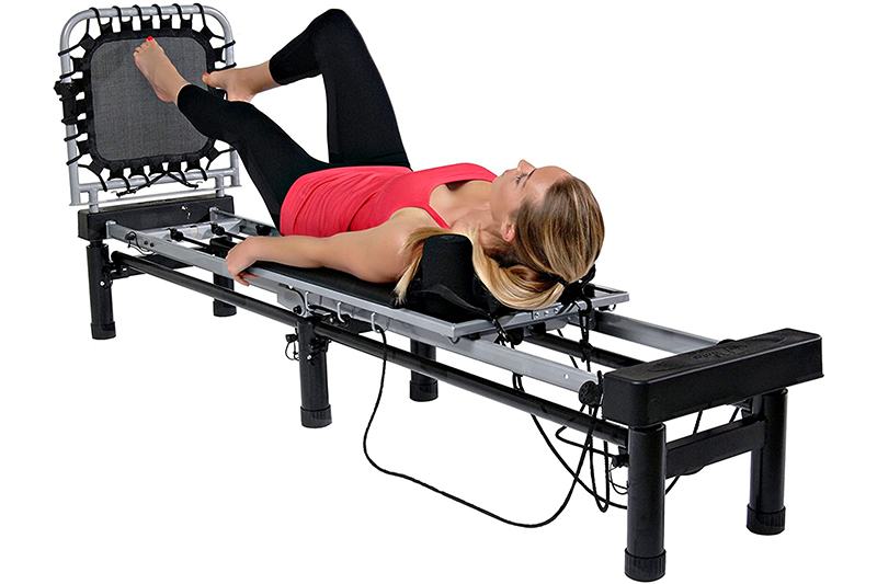 AeroPilates Reformer 266 on Pilates Reformers Plus Lady using AeroPilates Reformer 266, lying on back and jumping off the end rebounder.